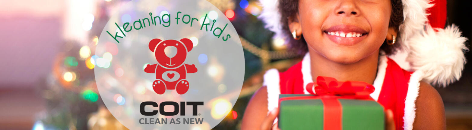 COIT Kleaning for Kids logo with young girl sitting in front of a Christmas tree holding a wrapped present looking at the camera.