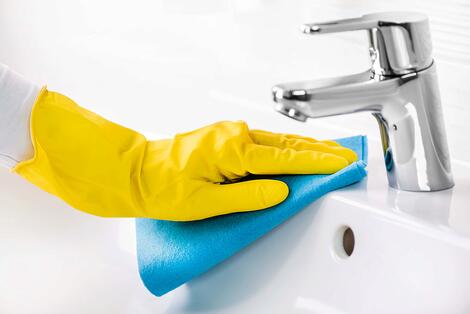Yellow Latex Gloved Hand Cleaning a Sink and Faucet with Disinfectant 