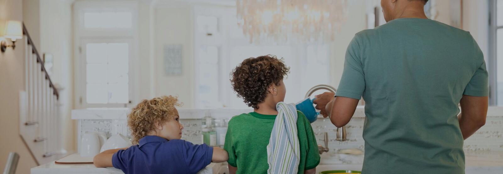 Children and father washing dishes at kitchen sink