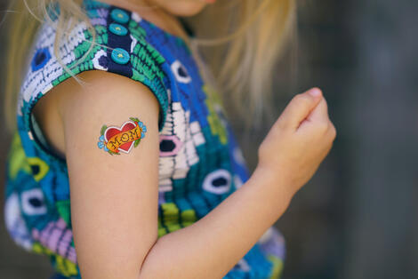 Selective focus photo of girl with temporary tattoo reading mom on upper arm
