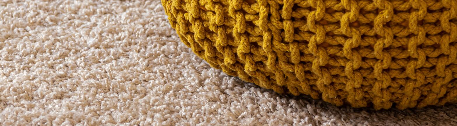 Yellow knitted bag on light colored carpet.